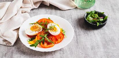 Light appetizer of tomatoes, boiled egg, cheese and arugula on a plate web banner photo