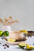 Cold coffee with lime wedges in a cup on the table vertical view photo