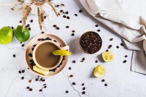 Cold coffee with lime wedges in a cup on the table top view photo