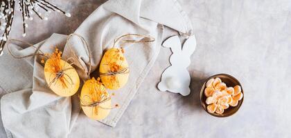 Easter eggs with dried flowers, bowl with marshmallows and bunny on gray top view web banner photo