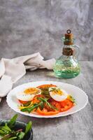 Light appetizer of tomatoes, boiled egg, cheese and arugula on a plate vertical view photo