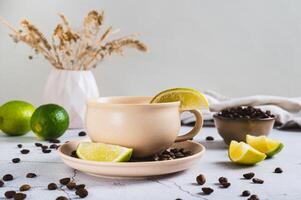 Cold coffee with lime wedges in a cup on the table photo