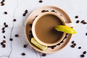 Close up of cold coffee with lime wedges in a cup on the table top view photo