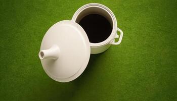 White tea pot on green grass background photo