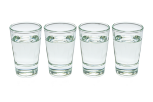 A Four clear glass shot glasses filled with water are lined up in row against transparency background, creating simple and clean composition png