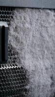 Cleaning the metal grid on the computer from dust with a close-up brush. A lot of dust is flying around the room. slow motion. video