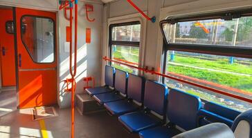 Interior of an empty city train carriage with blue seats and orange handrails. Passenger train. Empty seats in the carriage. Intercity. photo
