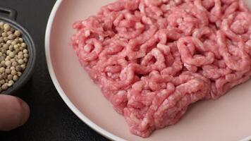 Stuffing raw beef or pork with salt and spices on a black background video