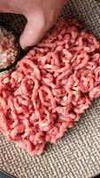Stuffing or ground raw beef or pork with spices on a black background video