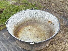 Rusty metal basin on outdoor ground surface weathered container in natural setting photo