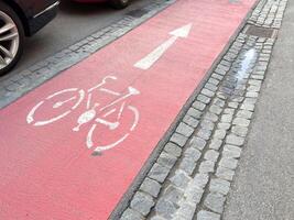 Red bicycle lane with arrow on cobblestone street photo