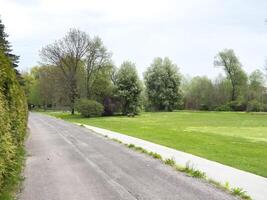 Tranquil park pathway with lush greenery on a cloudy day photo