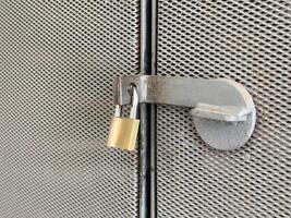 Metal gate with padlock on rusty mesh fence for security and protection photo