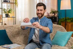 Young man happily tears an unnecessary document into pieces, feeling relieved and free from concerns photo