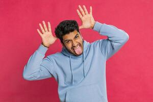 Funny comical Indian man making silly facial expressions, grimacing, fooling around, showing tongue photo