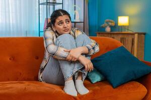 Indian woman on sofa holding head in hands frustrated exhausted I don't know gesture stressed photo