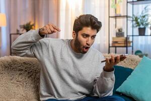 Man talking on phone via speaker mode gesturing emotionally and looking irritated during an argument photo