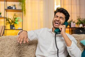 Indian man speaking loudly through 90s vintage phone, showing determination with strong expression photo