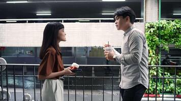 Asian office employee holding coffee talking with colleague while taking a break at the workplace talking with colleague video