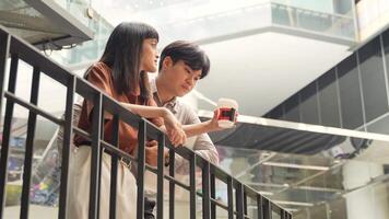 Asian office employee watching on mobile phone and talking with friend while having lunch break in the city while taking a break video
