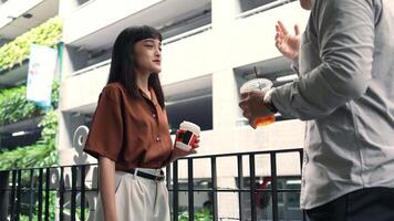 An office employee in casual style holding drink talking with colleague while taking a break at the workplace talking with colleague video