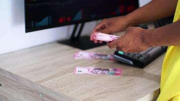 Hands Counting Currency On Wooden Desk Near Computer Screen video