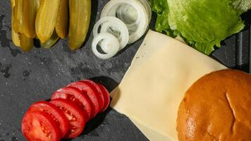 Fresh burger ingredients with juicy tomatoes, lettuce, onions, and cheese on dark surface, perfect for BBQ and picnic gatherings photo