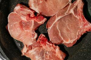 Raw pork chops in a pan, ideal for grilling or barbecuing, perfect for summer cookouts and rustic meals photo