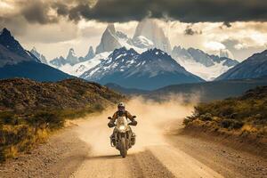 A motorcyclist rides through a dusty path in Patagonia, with majestic mountains and glaciers in the background. The atmosphere is charged, showcasing natures grandeur and the thrill of exploration. photo