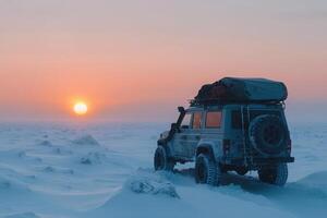 A rugged off-road vehicle parked on a snow-covered terrain as the sun sets in the background, casting a warm glow in the cold winter sky and highlighting the beauty of the frozen landscape. photo
