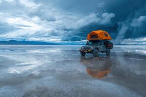 A rugged jeep equipped with a rooftop tent stands on a vast salt flat reflecting dark, stormy clouds. The scene captures the allure of adventure amidst natures majesty. photo
