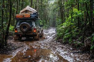 A rugged vehicle navigates a muddy and slippery trail in a lush rainforest. The scene showcases thick vegetation and a sense of adventure under rainy weather. photo