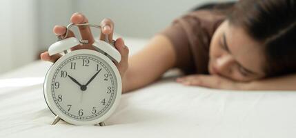 Lazy young woman close a clock alarm, lady is late appointment or work or class study, overslept, difficulty get up in mornings, time worried, not on time, sleepy, over due, Hurry up time photo