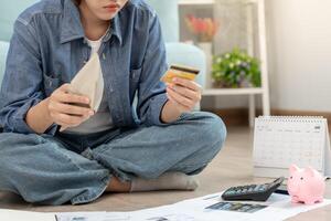 headache asian woman with large bills or invoices no money to pay to expenses and credit card debt. shortage, Financial problems, mortgage, loan, bankruptcy, bankrupt, poor, empty wallet. photo