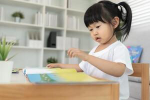 Happy Asian children relax read book at home. daughter and reading a story. learn development, childcare, laughing, education, storytelling, practice imagine reduce addiction mobile phone photo