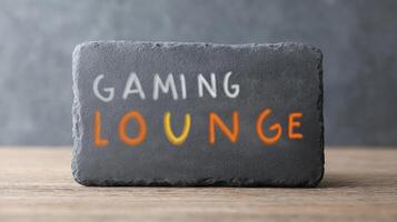 Stylish Slate Sign Displaying Gaming Lounge Text with Colorful Letters on Wooden Table Background photo