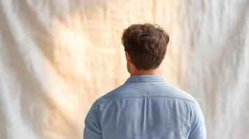 Young Man in Light Blue Shirt Facing Soft Neutral Background in Studio Setting with Natural Lighting photo