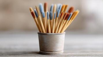 Collection of Colorful Paint Brushes in a Rustic Pot on a Wooden Surface photo