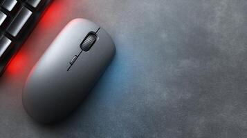 Sleek Black Computer Mouse on a Dark Gray Surface with Keyboard and Ambient Lighting Effects photo