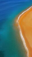 Aerial View of Vibrant Orange Sand Meeting Turquoise Water on Serene Beach Shoreline photo