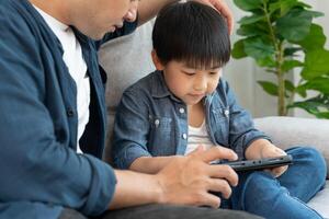 Happy single father playing teach using tablet with the little boy. family is happy and excited in the house. Father and son having spending time together, Good daddy , addiction fix, handle photo