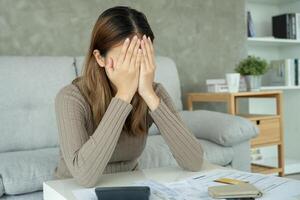 Stressed and headache asian woman with large bills or invoices no money to pay to expenses and credit card debt. shortage, Financial problems, mortgage, loan, bankruptcy, bankrupt poor empty wallet. photo