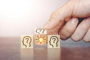 Hand flip over wooden cube block with head human symbol and light bulb icon.Brainstorming ideas present new ideas among teams and communicate creativity and innovation with copy space. photo
