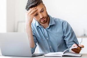 Tight Schedule. Tired Businessman Checking Business Appointments In Notepad At Office, Planning His Working Timetable, Copy Space photo