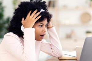 Shocked African Girl At Laptop Touching Head Having Internet Connection Problem During Online Class At Home. Computer Issue photo