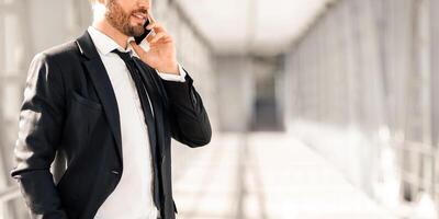 Unrecognizable businessman talking on mobile phone while waiting for departure in airport, panorama with copy space. Cropped of man in suit having conversation with business partners on smartphone photo