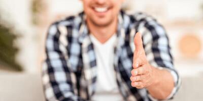 Closeup of unrecognizable businessman offering hand for greeting. Friendly executive employer ready for handshake, welcoming client, coworker or partner. Successful deal, introduction concept photo