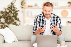 Virtual Conversation. Portrait of young manager having online call on laptop, talking to webcam. Cheerful man explaining something to client and gesturing, sitting on the sofa at his house photo