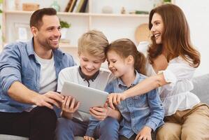 Parents And Children Using Tablet Computer Sitting On Sofa Watching Film Together At Home. Family Weekend Concept photo