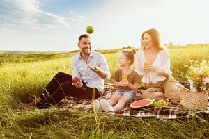 Portrait of excited guy juggling with apples, showing tricks to his family during picnic, free space photo